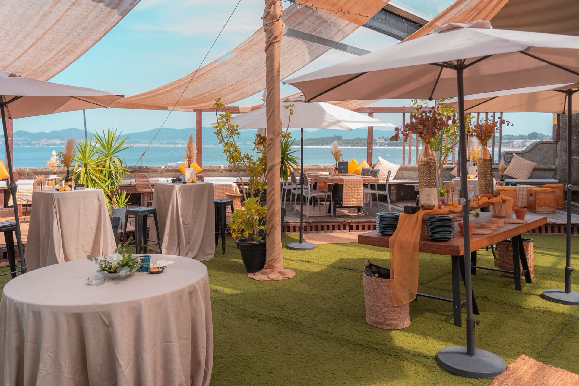 Terraza de Finca Fontaíña montada para una celebración, con mesas altas, sombrillas y la ría de Vigo al fondo