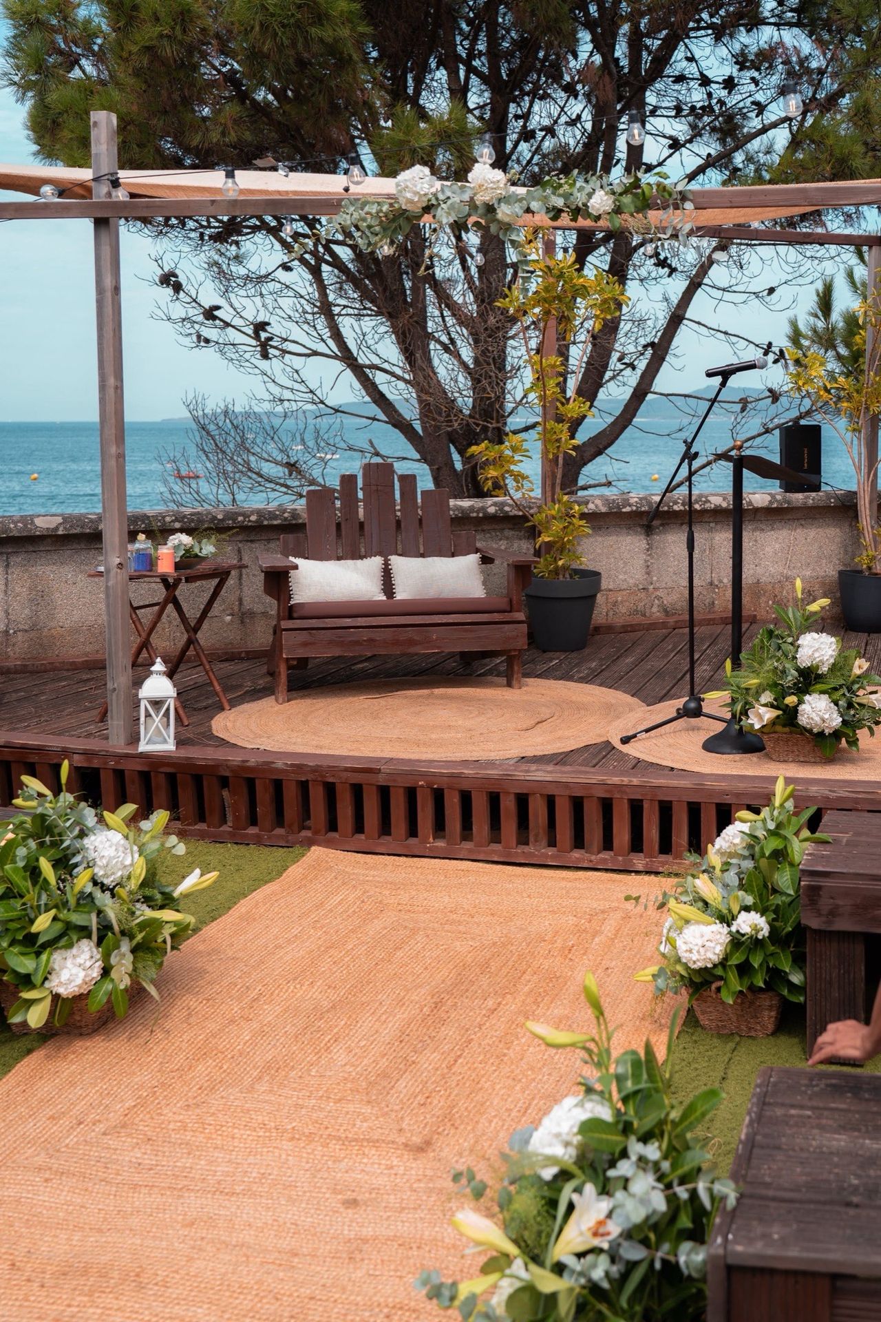 Zona de ceremonia con pasillo de yute, flores blancas y el mar de Vigo al fondo