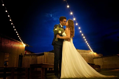 Novios besándose de noche bajo las luces de la terraza de Finca Fontaíña