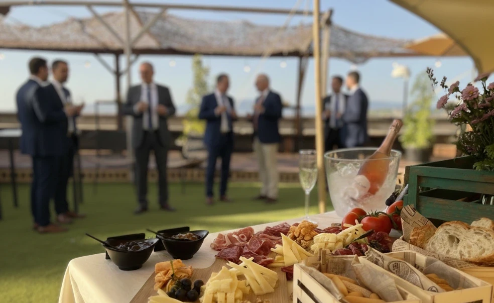 Invitados conversando junto a una mesa de quesos y embutidos en la terraza de Finca Fontaíña