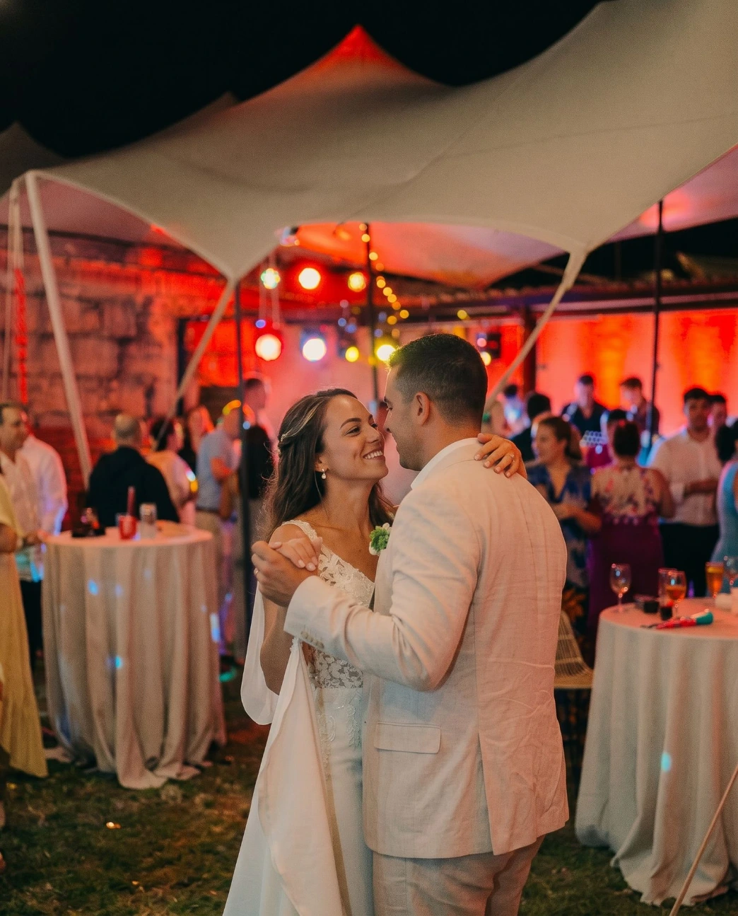 Novios bailando por la noche bajo la carpa, con luces de fiesta e invitados alrededor, en Finca Fontaíña